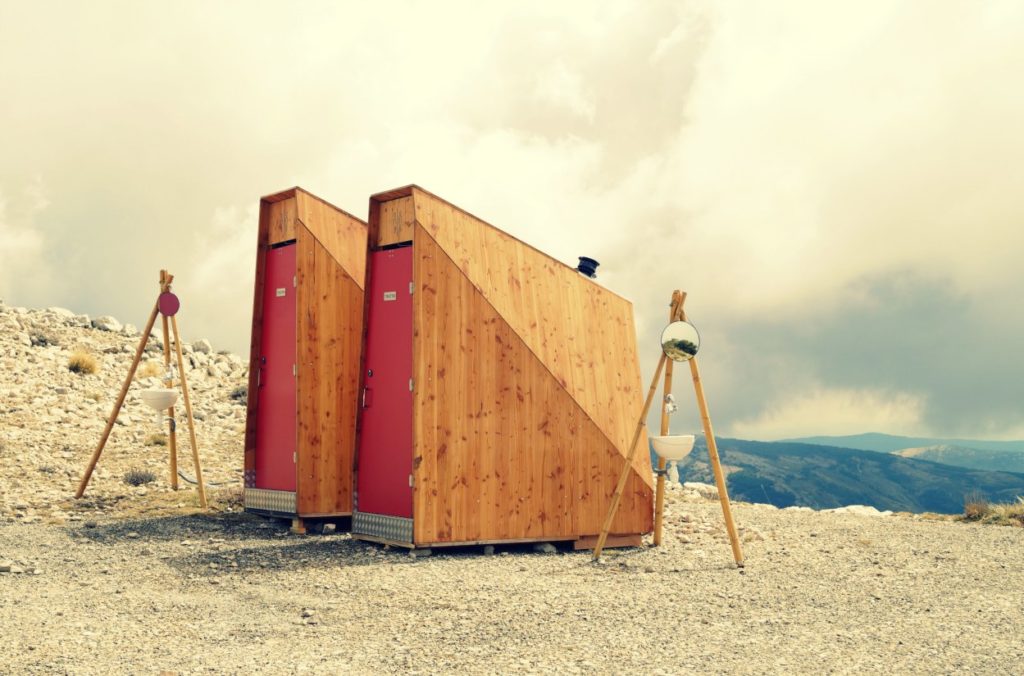 toilettes sèches en bois avec porte rouge dans la nature